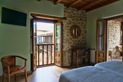 1 dormitorio con 1 cama y puerta a un balcón en Los Campos Vivienda Vacacional en Cangas de Onís