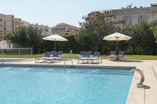 a swimming pool with chairs and umbrellas next to at Alua Leo in Can Pastilla