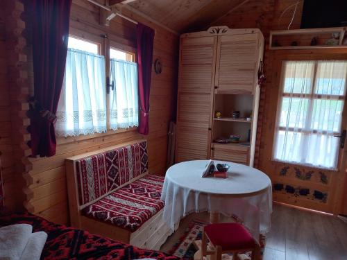 Zimmer mit einem Tisch in einem Zimmer mit Fenstern in der Unterkunft Cabanuta Casuta din Povesti in Bran