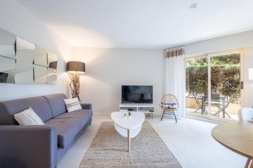 un soggiorno con divano e tavolo di SERRENDY Garden level with swimming pool a Cannes