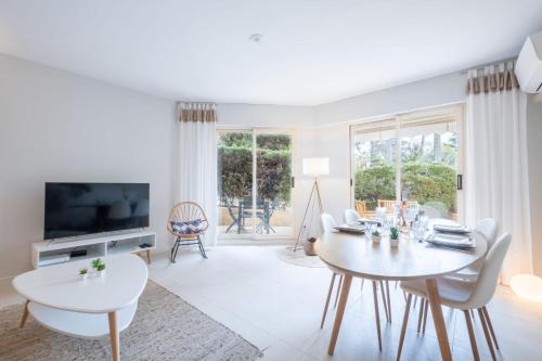 a white living room with a white table and chairs at SERRENDY Garden level with swimming pool in Cannes