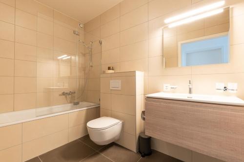 a bathroom with a toilet and a sink and a mirror at Les Terrasses de Lavaux 1 - Appartement de luxe avec vue panoramique et piscine in Puidoux