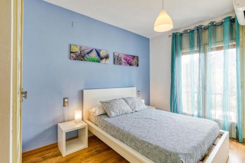 a blue bedroom with a bed and a window at Apartamento Roses Victor in Roses