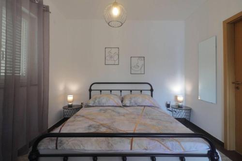 ein Schlafzimmer mit einem Bett mit zwei Lampen an zwei Tischen in der Unterkunft Apartman Studio Pesja in Omišalj