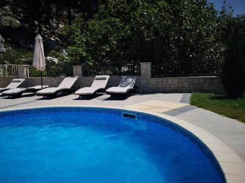 a swimming pool with lounge chairs and an umbrella at Villa Fabry in Ploče