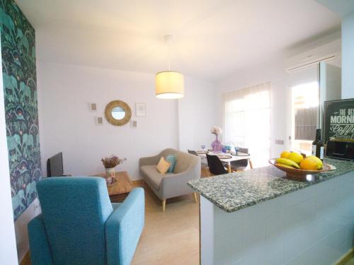 een keuken en een woonkamer met een blauwe stoel en een tafel bij Apartamento Residencial Al Andalus 117, La Barrosa, Chiclana, Incluye parking a unos metros del mar in Chiclana de la Frontera