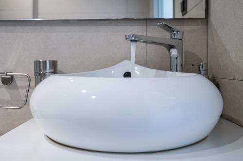 a white sink in a bathroom with a faucet at Milva Apartments in Kos Town
