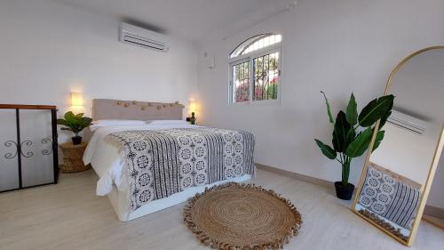 a white bedroom with a bed and a window at New Boho Home with Pool, Balcony and Private Garden in Nerja