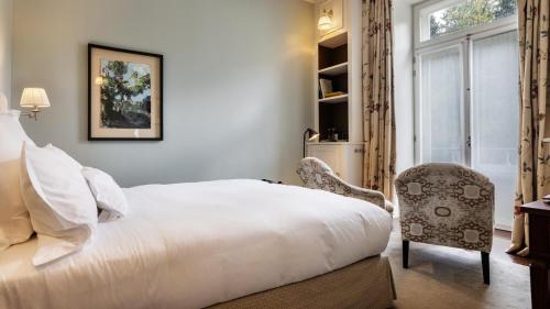 a bedroom with a bed and a chair and a window at Vidago Palace in Vidago