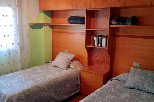 ein Schlafzimmer mit 2 Betten und einem Bücherregal in der Unterkunft Apartamento para 6 personas en Barbastro in Barbastro