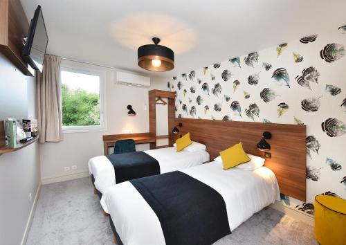 two beds in a hotel room with white and black at Contact Hôtel Astréa Nevers Nord et son restaurant la Nouvelle Table in Varennes Vauzelles
