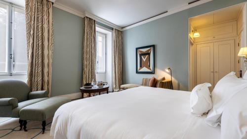 a bedroom with a large white bed and a chair at Vidago Palace in Vidago