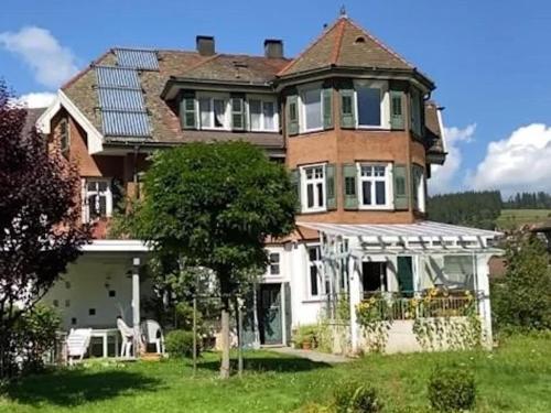 ein großes Backsteinhaus mit einer Veranda auf einem Rasen in der Unterkunft Ferienwohnung am Bühl 1 in Lenzkirch
