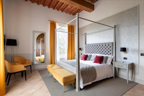 um quarto com uma cama de dossel e uma cadeira em Relais Villa Grazianella | UNA Esperienze em Acquaviva