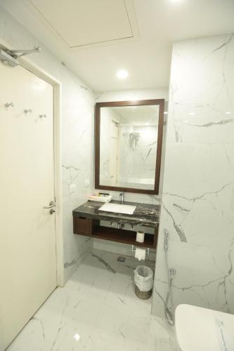 a white bathroom with a sink and a mirror at Hotel Meraden Grand in Varanasi