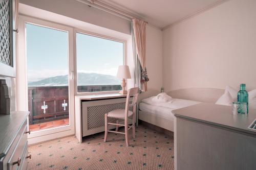a bedroom with a bed and a large window at Mittelburg Wellnesshotel in Oy-Mittelberg