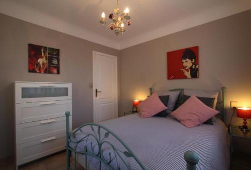 - une chambre avec un lit doté d'oreillers roses et d'un lustre dans l'établissement Gite Moulin Urketa, à Ayherre