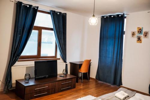 een slaapkamer met blauwe gordijnen en een tv op een dressoir bij LONDOF Housing City Center Brasov in Braşov