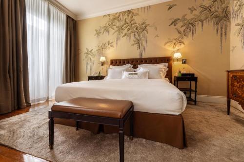 a bedroom with a large bed with white sheets and a bench at Vidago Palace in Vidago