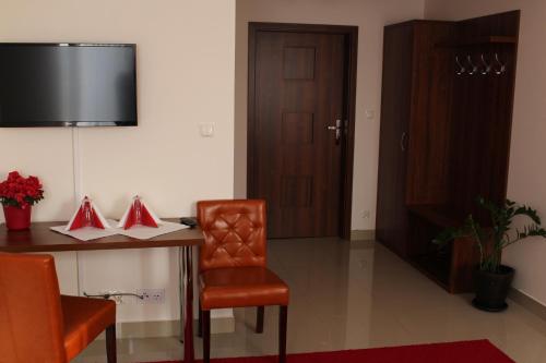 a room with a table and a chair and a television at Belweder in Białystok
