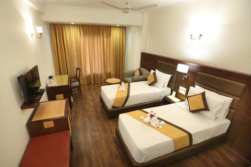 a hotel room with two beds and a couch at Hotel Meraden Grand in Varanasi