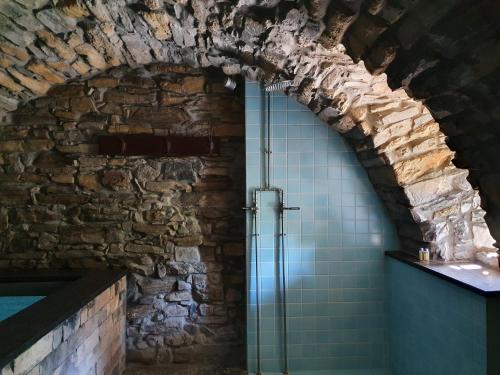 a bathroom with a glass shower in a brick wall at Albergo Diffuso Ca' Spiga in Laglio
