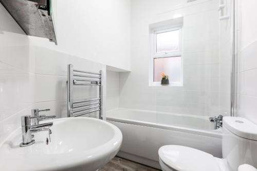 baño blanco con lavabo, bañera y aseo en Clayton House - Spacious home near Etihad Stadium en Mánchester