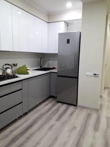 a kitchen with white cabinets and a stainless steel refrigerator at Telecentru, panoramic apartment in Chişinău
