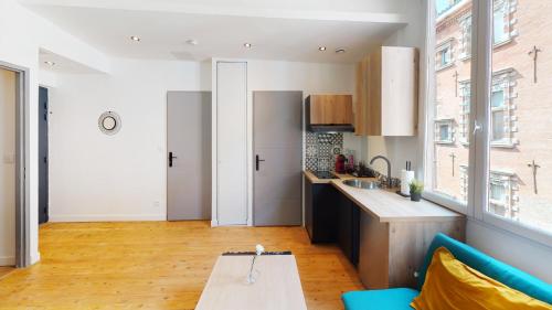 a kitchen and living room with a couch and a table at Hypercentre Toulouse 6 joli appartement climatisé et équipé in Toulouse