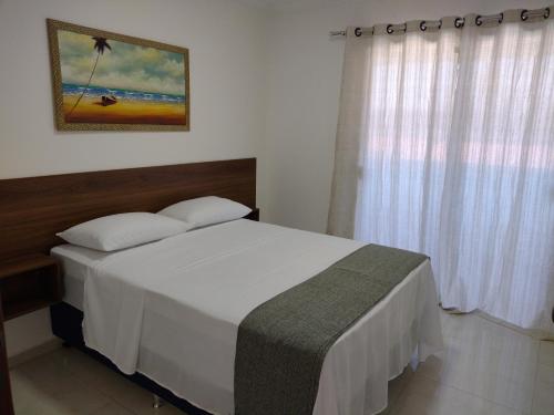 a bedroom with a white bed and a window at Residencial Secret Point in Praia do Frances