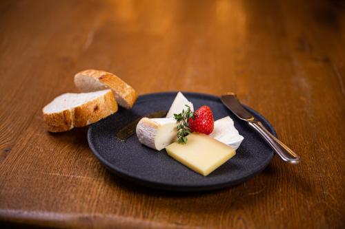 a plate with cheese and bread and a strawberry on it at Mittelburg Wellnesshotel in Oy-Mittelberg