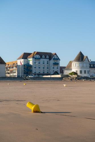 a yellow object on a beach with buildings in the background at ibis Styles Deauville Villers Plage in Villers-sur-Mer