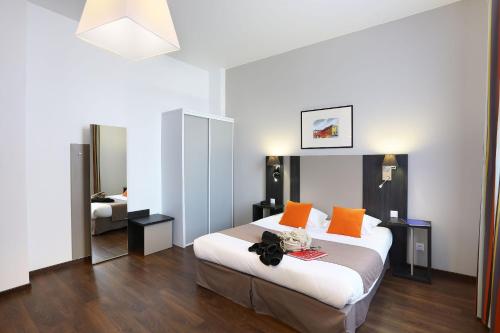 a bedroom with a large bed with orange pillows at Appart Hotel Odalys City Toulouse Colombélie in Toulouse
