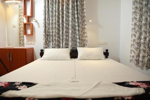 a bed with two pillows in a bedroom with curtains at Marari Casa Almare in Mararikulam