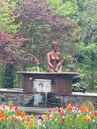 a statue of a man sitting in a fountain in a garden at Sur un air d'eau in Spa