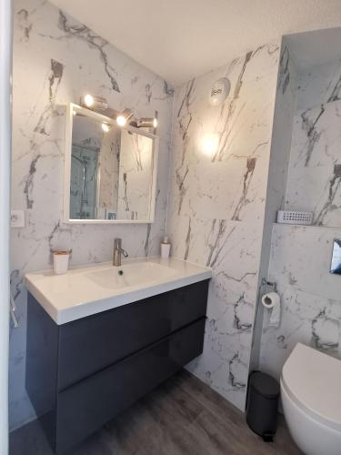 La salle de bains est pourvue d'un lavabo et d'un mur en marbre blanc. dans l'établissement Saint Tropez City Loft, à Saint-Tropez