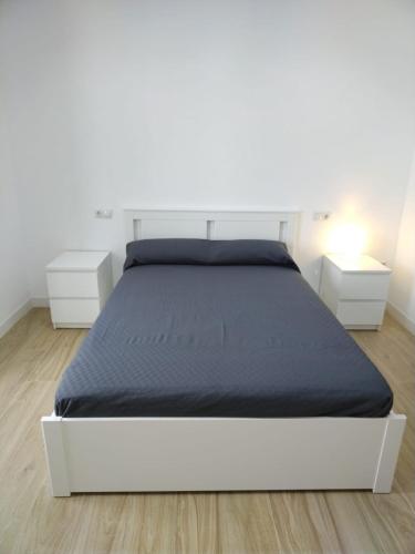 Cama blanca en habitación blanca con 2 mesitas de noche en CASTRO Suites Osuna, en Osuna