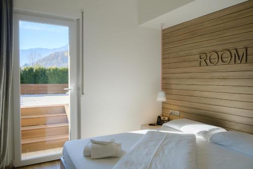 Schlafzimmer mit einem Bett mit einem Kopfteil aus Holz und einem Fenster in der Unterkunft B612 in Levico Terme