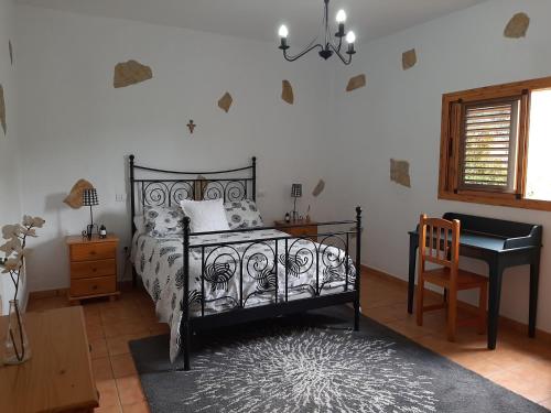 um quarto com uma cama, uma secretária e um piano em Peaceful house set on a vineyard & work friendly em Valsequillo