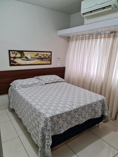 a bedroom with a bed and a window with a curtain at Estúdio Ibiza em Jatiúca in Maceió