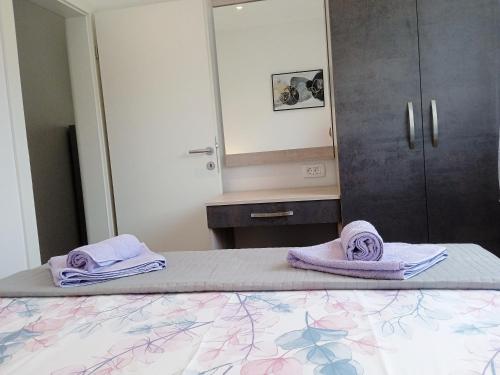 - une chambre avec un lit et des serviettes pourpres dans l'établissement Apartmentt Vinko Bilota, à Seget Vranjica