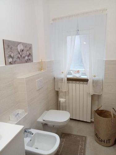 a white bathroom with a toilet and a window at Casa marlene in Orino