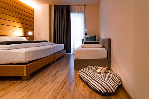 a hotel room with two beds and a suitcase on the floor at Lake Front Hotel Mirage in Riva del Garda