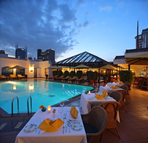 ein Restaurant mit einem Pool mit Tischen und Stühlen in der Unterkunft Sarova Stanley in Nairobi