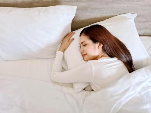 a woman laying in bed with a pillow at Hop Inn Hotel Cebu City in Cebu City