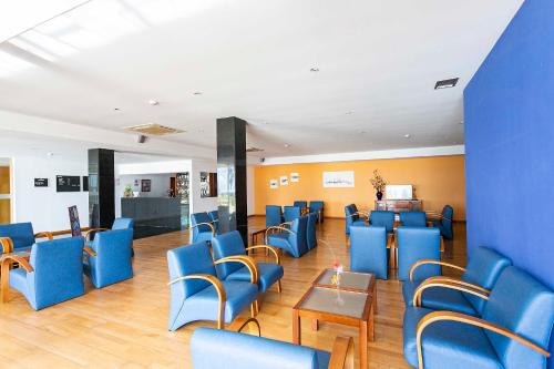 a waiting room with blue chairs and a table at Hotel Colombo in Vila do Porto