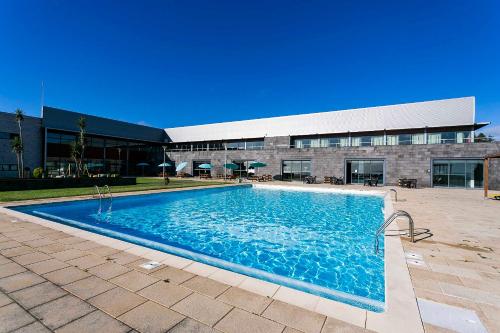 a swimming pool with a large blue building at Hotel Colombo in Vila do Porto