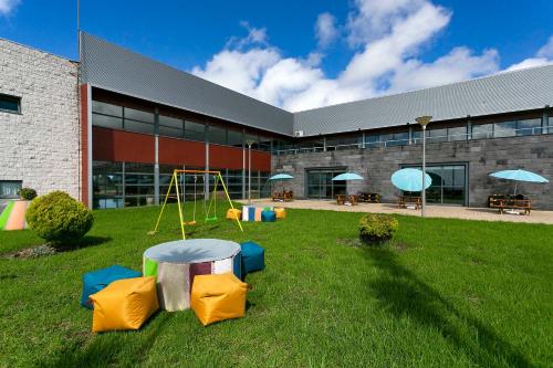 a building with a playground in the grass in front of a building at Hotel Colombo in Vila do Porto