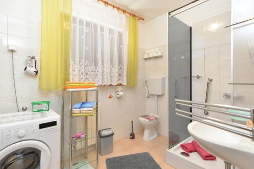 a bathroom with a sink and a washing machine at Apartments Anka 1223 in Peroj