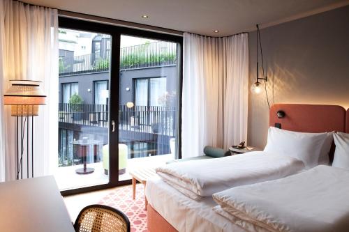 a hotel room with two beds and a large window at Hotel Indigo Vienna - Naschmarkt, an IHG Hotel in Vienna